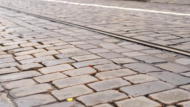 Cobblestone street with passing cars. Narrow cobblestone street, crawling across urban pavement with distant cars passing in background