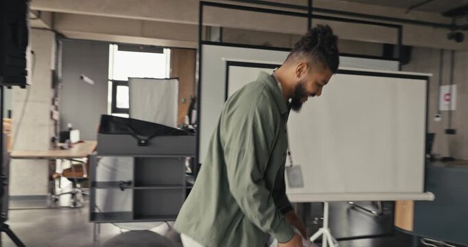 A man performs dance moves while engaging with people during a talk in a studio setting
