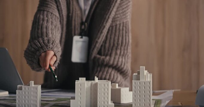Hands arranging architectural models on an office desk