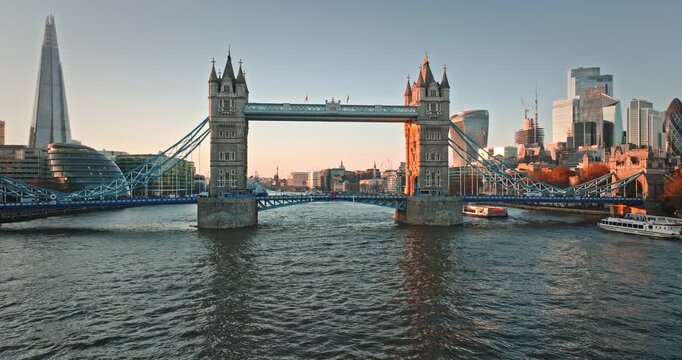 Tower Bridge and The Shard dominate London skyline, capturing an iconic cityscape panorama from an aerial perspective over flowing River Thames at golden hour sunset. United Kingdom travel destination