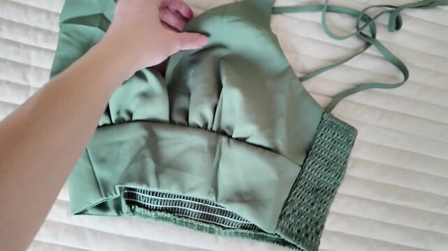Female hand showcasing sage green bralette top, front and back garment details