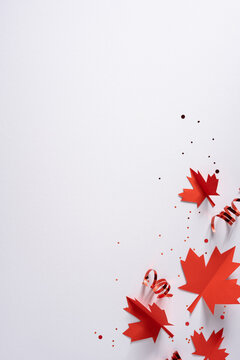 Canada independence day celebration with red maple leaf decorations, curled ribbon and confetti on vertical white backdrop