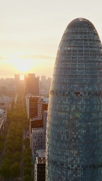 Torre Glories Barcelona glass tower sunset golden light skyline Spain aerial slow motion futuristic architecture business district landmark travel Catalonia cityscape vertical