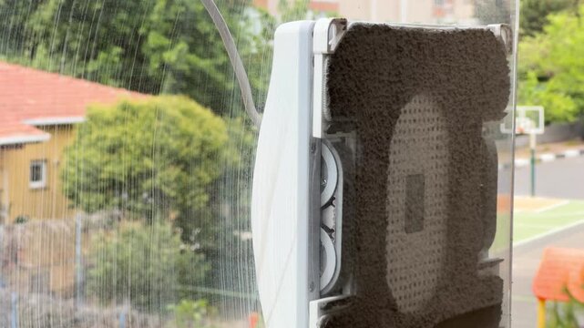 Smart square window cleaning robot cleaning the exterior glass pane of a balcony.