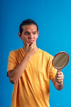 Young man seeing problem looking himself in mirror