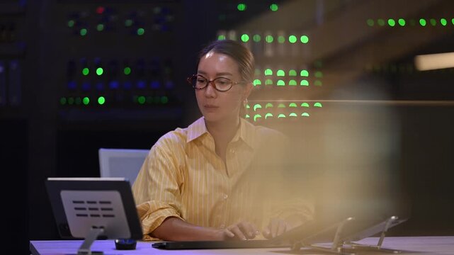 Stressed female it technician working late in a server room and feeling overwhelmed by system failure