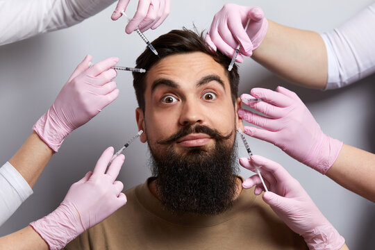 Conceptual beauty and cosmetology image of hands of several doctors holding syringes over male face. Beauty and Cosmetology concept. Cosmetic procedures mesotherapy