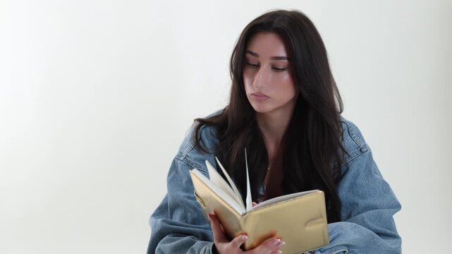 Education and learning concept with a young woman intently reading a book in a studio setting. This focused student is studying for exams, knowledge acquisition and academic pursuit. The image concent