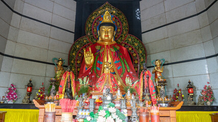 Naklejka premium Golden Guan Yin Bodhisattva Statue with Red Robe inside Buddhist Temple