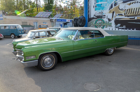 Striking green Cadillac DeVille 1965 convertible. Its massive presence, chrome detailing, and sweeping lines exemplify the grandeur of classic design