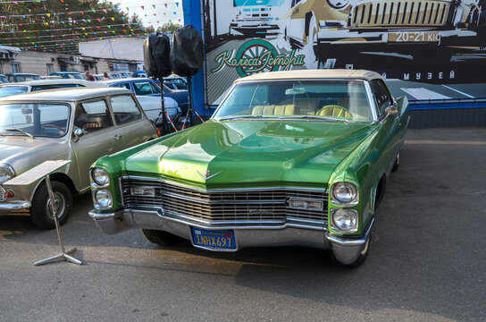 Striking green Cadillac DeVille 1965 convertible. Its massive presence, chrome detailing, and sweeping lines exemplify the grandeur of classic design