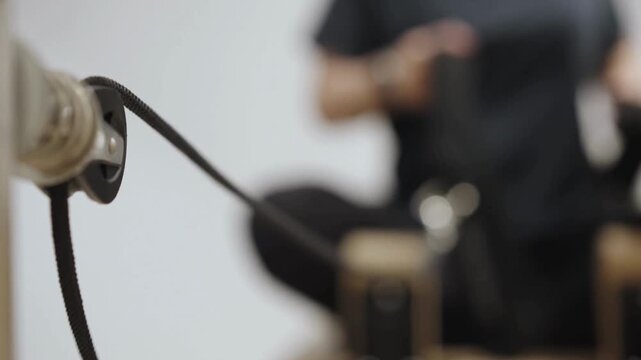 Detail of fitness equipment cable with a person doing seated rows.