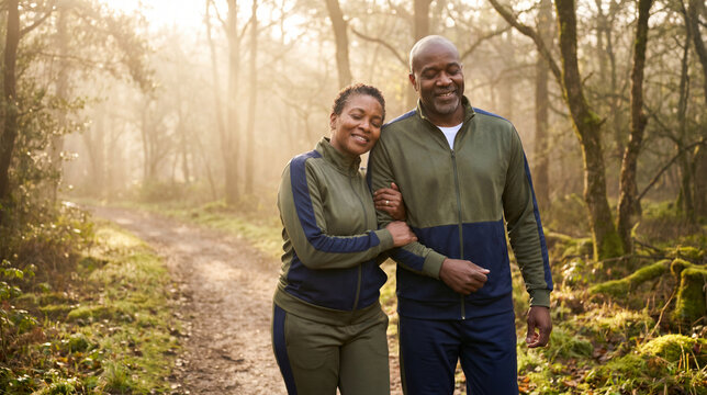 Happy senior african american couple walking in a forest, holding arms, looking at each other, smiling, close up