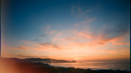 Fototapeta premium Abstract blurred sunset over the sea with distant mountains and orange sky