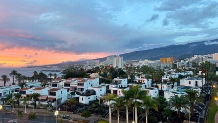 Tenerife coastal resort city at dusk with palm trees and mountains © Ольга Клецкова