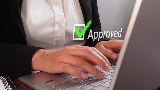 Close-up of a businesswoman working on her computer with an animated checkmark and the word "approved"