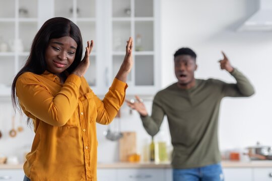 Upset Black Woman Showing Displeasure While Listening To Argument From Man In Kitchen. Emotional Tension Between Two Adults In Domestic Setting Highlighting Conflict Situation.
