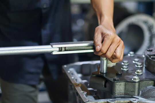 Mechanic Hands Using Torque Wrench on Engine Block.