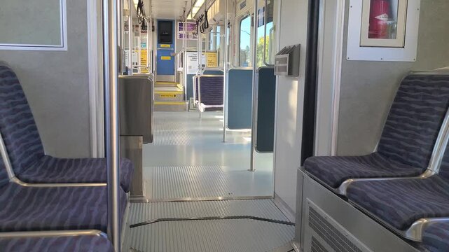 Light rail train interior with empty seat, traveling through the city during day time