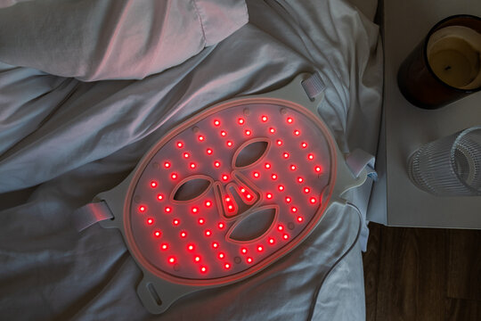 Red light therapy face mask on bed at home