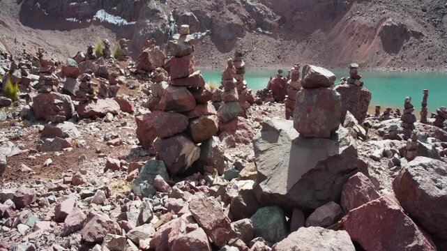 Traditional stone cairns or apachetas overlooking a turquoise glacial lake in Peru