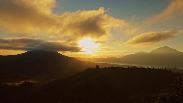 Timelapse Sunrise Above Gunung Batur and Gunung Abang With Golden Clouds Illuminating Volcanic Landscape and Misty Mountain Horizon