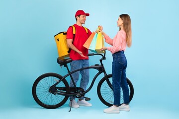 Fototapeta premium Smiling Young Man And Woman Exchanging Colorful Shopping Bags While Standing Next To Bicycle In Studio. Cheerful Emotion Representing Lifestyle Choices In Modern Retail Environment, Weight Loss
