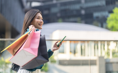 Online shopping, Smiling asian woman holding shopping bags using smartphone, digital payment...