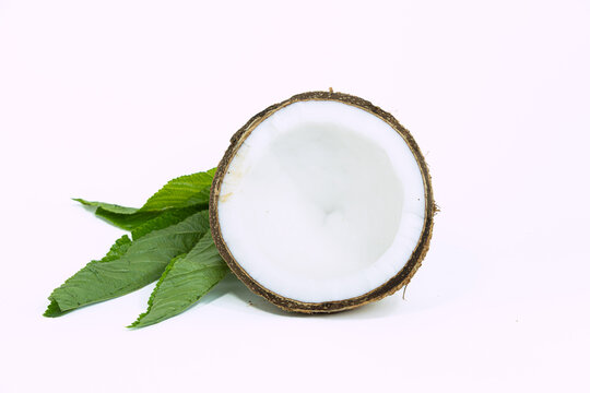Freshly cut half coconut with green leaves isolated on white background