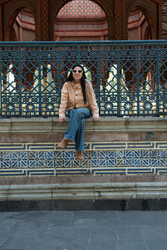 Woman smiling sitting on kiosco morisco architectural wall