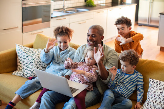 Happy father with four children video calling on laptop at home