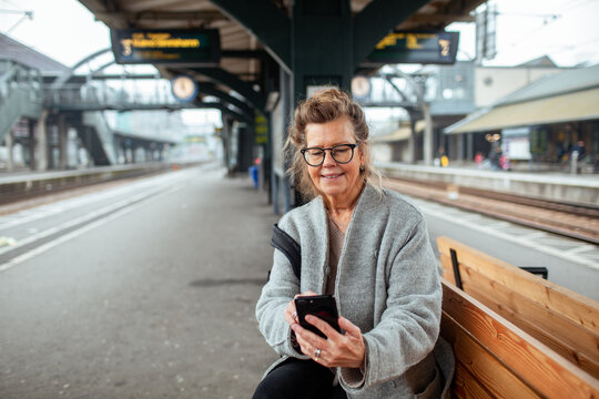 Senior woman using smartphone at train station platform