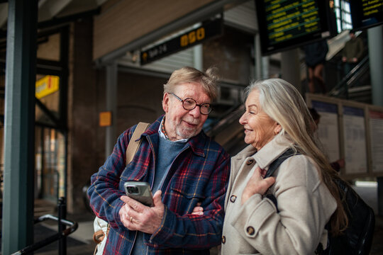Senior couple using smartphone at train station