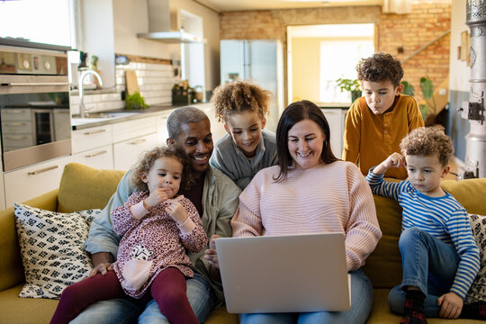 Happy parents and children watching a laptop on the sofa at home