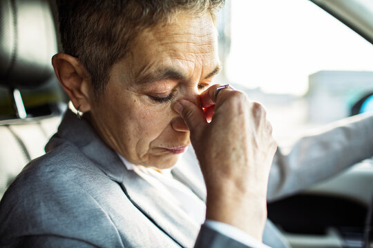 Stressed adult driver rubbing eyes in car