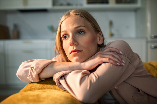 Pensive young woman resting on sofa at home
