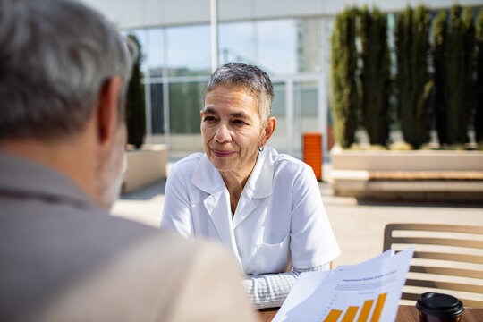 Senior female doctor consulting patient outdoors at clinic