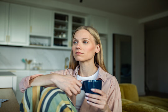 Thoughtful woman with coffee mug in home kitchen