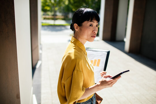 Businesswoman checking smartphone outside office building