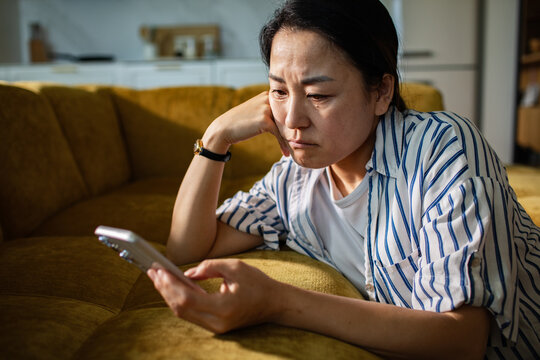 Concerned woman reading message on smartphone at home