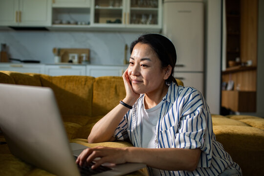 Smiling woman using laptop on couch at home