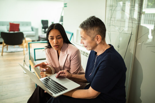 Two colleagues collaborating on laptop in creative office