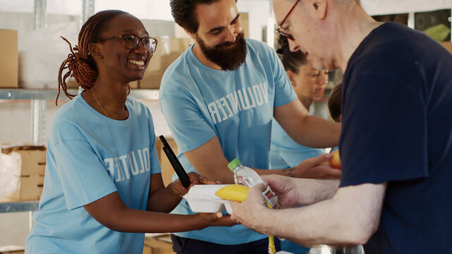 Friendly volunteers distribute generous food donations to homeless people showing impact of charitable works, close-up of voluntary individuals serving and sharing warm meals to the less fortunate.