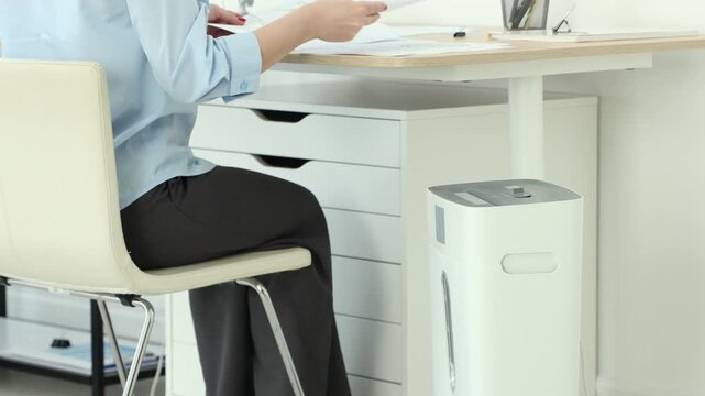 Woman destroying documents with paper shredder in office, closeup