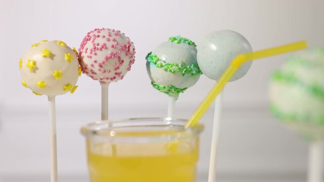 Tasty cake pops and juice on light background, selective focus