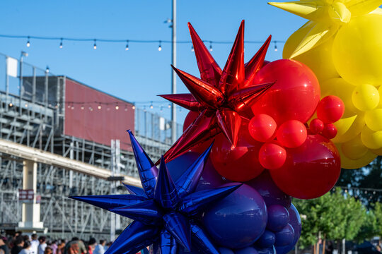 Colorful starburst and round balloons decorate a stadium during a Pride Month celebration