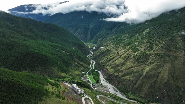 Aerial view of mountain river flowing at the bottom of steep deep green valley in Daocheng Yading China