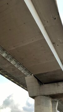 Low-angle view of a modern concrete Pumarejo bridge with steel beams and support pillars silhouetted against a soft sunset sky with clouds, creating an urban infrastructure background.