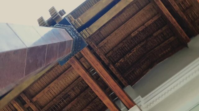 Old historic wooden pattern design roof ceiling of aged architecture building with columns from stone. Low angle view 