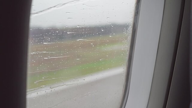 Close up view of raindrops moving on the window of airplane, plane flying in rainy day, 4k slow motion footage travel concept b roll shot.